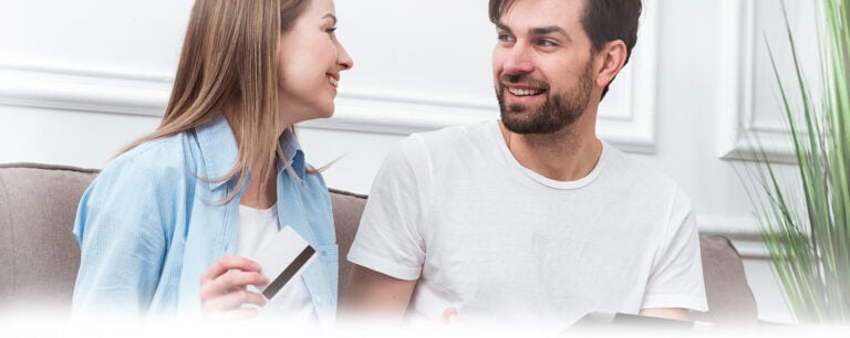 Smiling couple holding a credit card, representing seamless online payment experiences with AGMS processing.