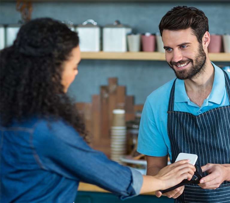 Customer taps phone for contactless payment on a terminal. AGMS offers secure merchant payment processing.