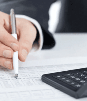 Hand with pen reviewing financial data with calculator. AGMS payment processing & business solutions.