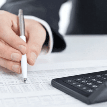 Hand with pen reviewing financial data with calculator. AGMS payment processing & business solutions.